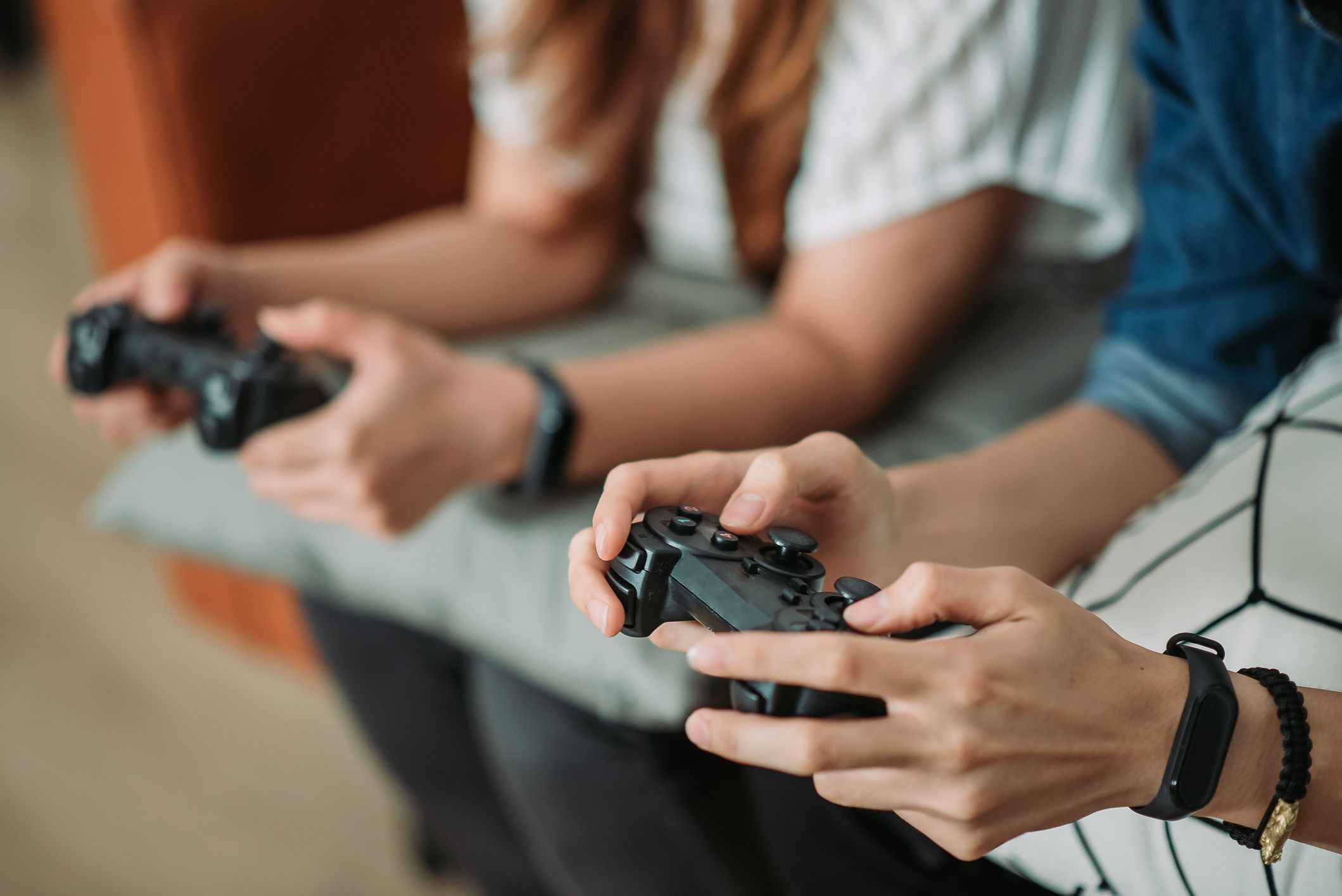 Mains de jeunes personnes jouant au jeu vidéo, avec une manette noire